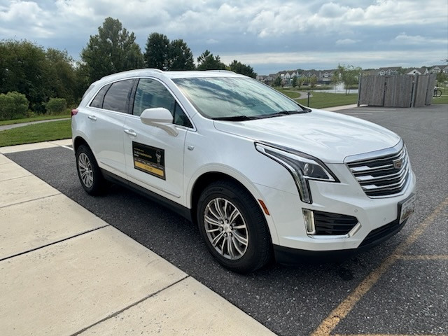 The white Cadillac XT5 with the Top Hat Transportation door sign